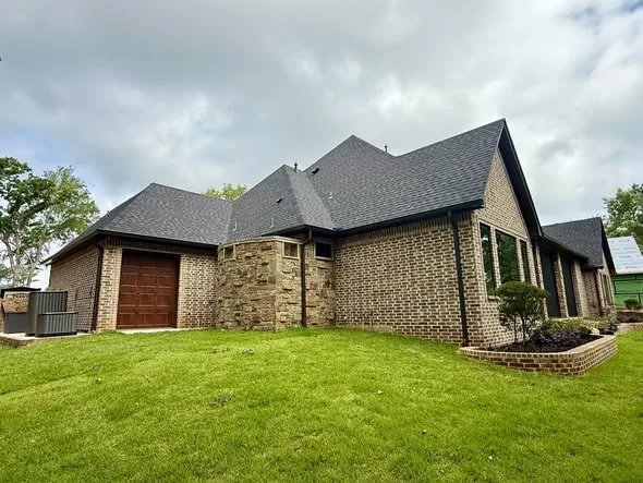 Dark gutters and downspouts around a brick home and garage