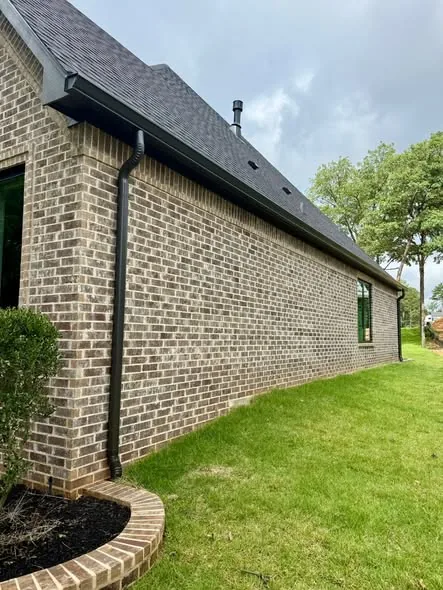 Black gutter and vertical downspout along a brick house wall