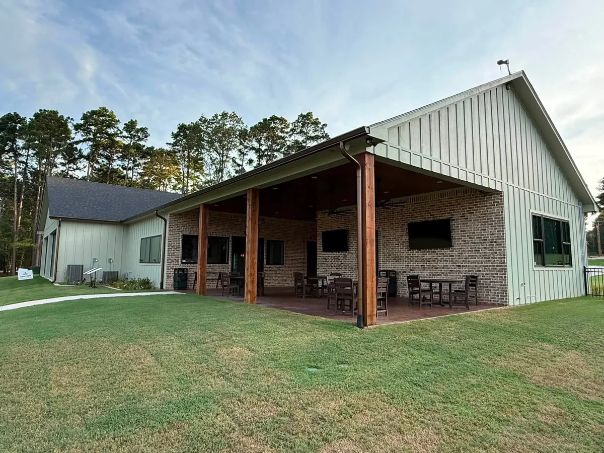 Dark gutter and downspout beside timber posts on a brick commercial porch