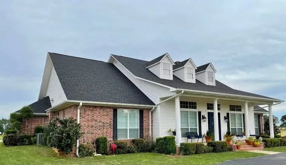 White gutters along the front porch of a brick home with three dormers