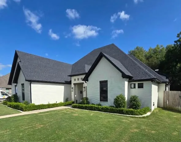 Dark gutters and downspouts on a white brick house with steep gables